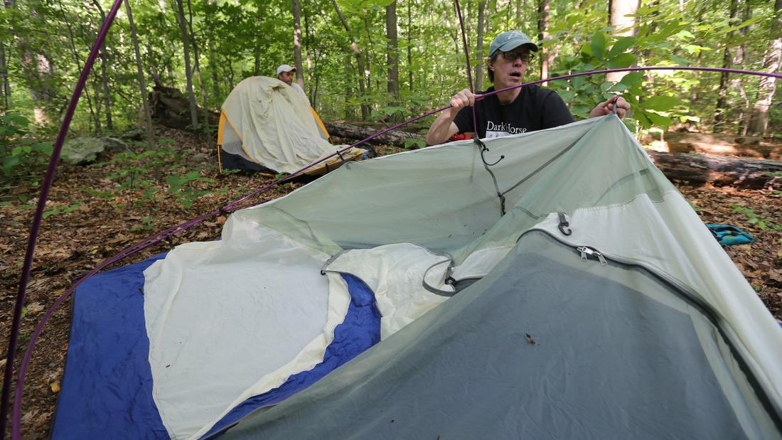 Emerson tries to remember how to set up his tent at the Rocky Run camping area on the Appalachian Trail as an afternoon rain shower moves through the area, as Walter Cumming works on his tent in the background. The tents were re-packed in favor of a wood shelter shortly after they went up. Ben Gray / bgray@ajc.com