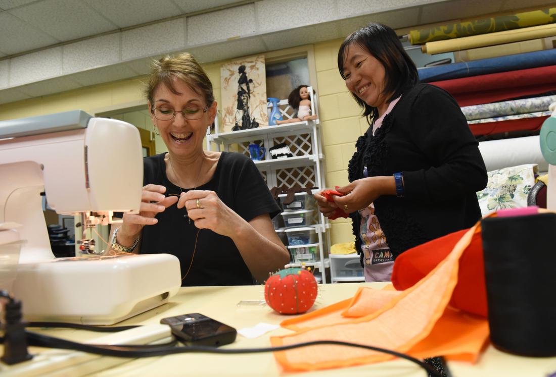 Cathy Palmer (left) laughs as she helps Zil Hing, from Burma, at Refugee Sewing Society in Clarkston International Bible Church on Tuesday, May 19, 2015.  HYOSUB SHIN / HSHIN@AJC.COM