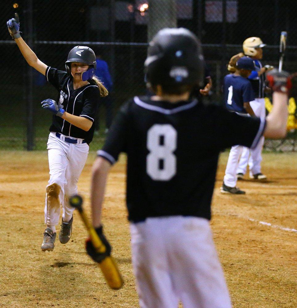 Sam Davis, his finger held high, prances back to the dugout after stealing home and tying a game. No. 8, brother Reuben, is equally excited. Curtis Compton / ccompton@ajc.com