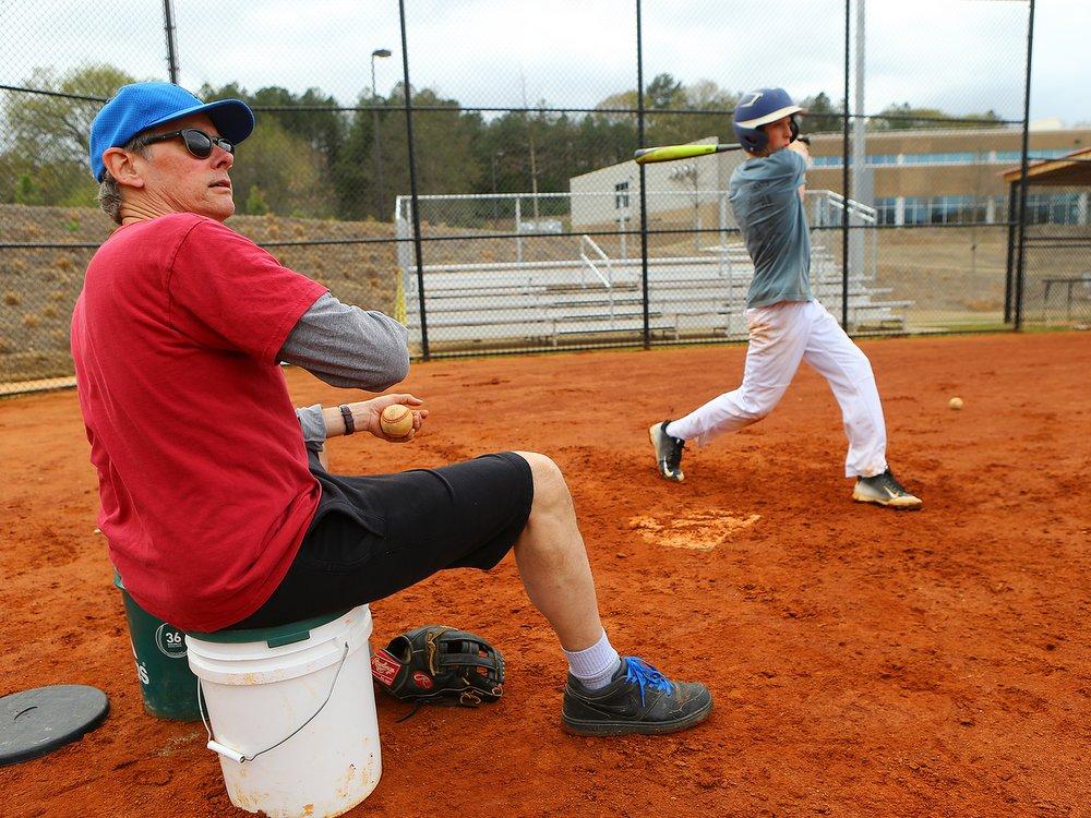 Eighth-grader Joseph McGill rips a shot to right-center. In some practices,  the coach sat on a bucket and soft-tossed baseballs to batters. Curtis Compton / ccompton@ajc.com