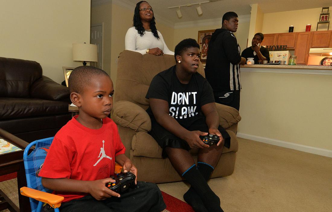Walter plays NBA 2015 with his cousin, Jaylen, 5, as his aunt Nitika watches. Kent D. Johnson/AJC